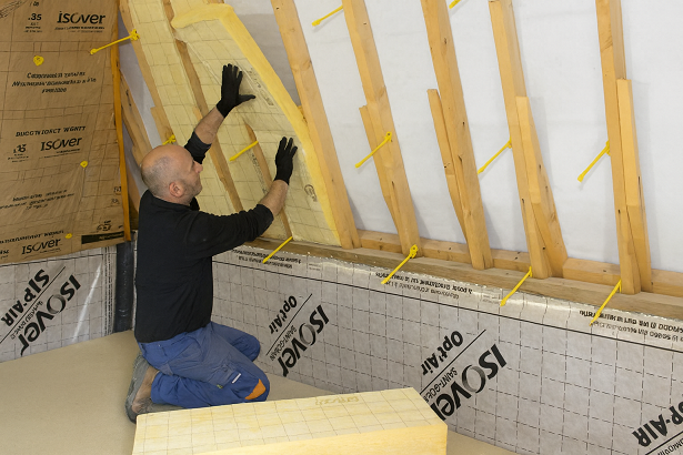 Homme en train de poser de l'isolation à l'intérieur.
